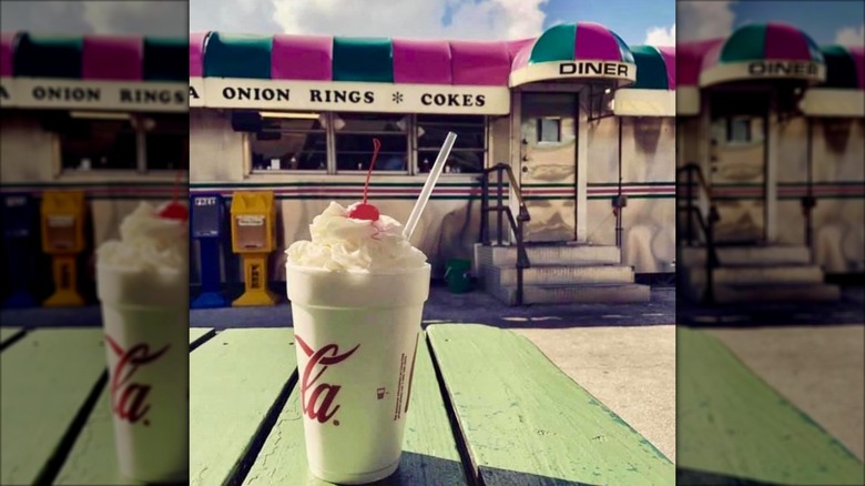 Exterior of Angel's Dining Car in barckground with pink and green awning and close up of an old fashioned ice cream shake with straw and cherry