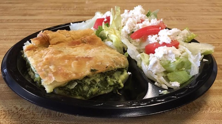 Greek Salad topped with feta and slice of Greek spinach pastry on a black plate from Pappas' Grill