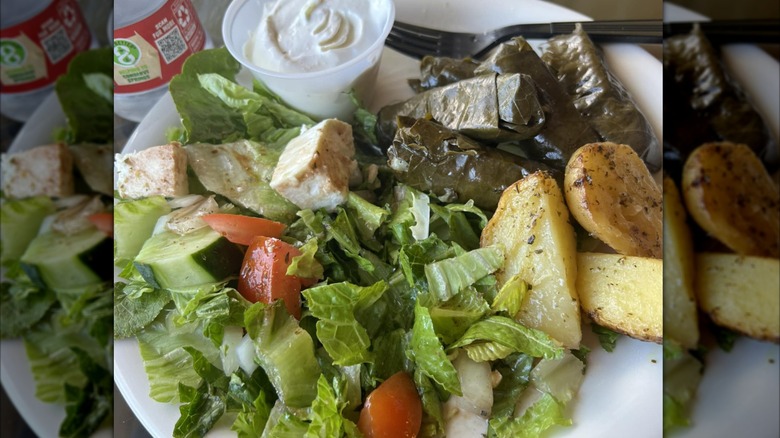 Dolmades, roasted potatoes, and a salad with chicken on a white plate from Antonio's Greek Bakery & Cafe