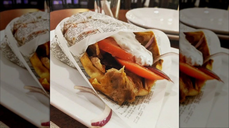 Gyro wrapped in paper on a white plate from It's Greek 2 U Grill