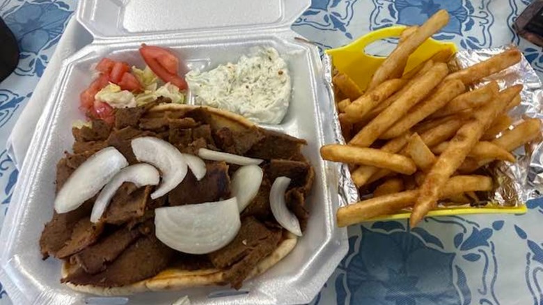 Gyro lunch plate with side of French fries and tzatziki in a to-go container at Adel's Gyros Pub & Grill