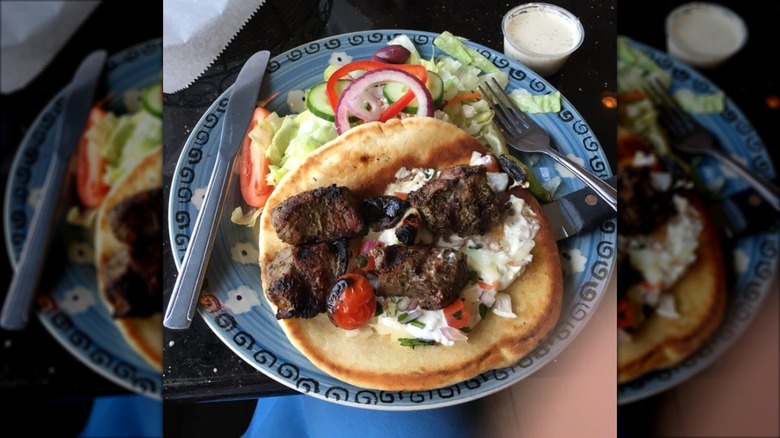 Lamb kabob with Greek salad on a blue plate from Esperia Grill