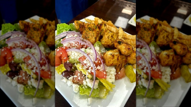 Greek salad and roasted meat on a white plate from Simply Delicious
