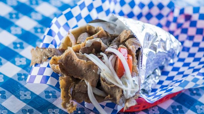 Gyro from Greek House wrapped in foil on a blue and white checkered piece of butcher paper