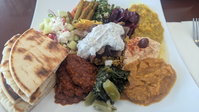 Mezze plate sampler from Athenian Deli & Restaurant with various dips, salads, and fresh pita