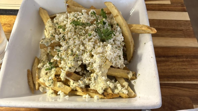 Loaded feta fries from Mina & Dimi's Greek House in a square white bowl