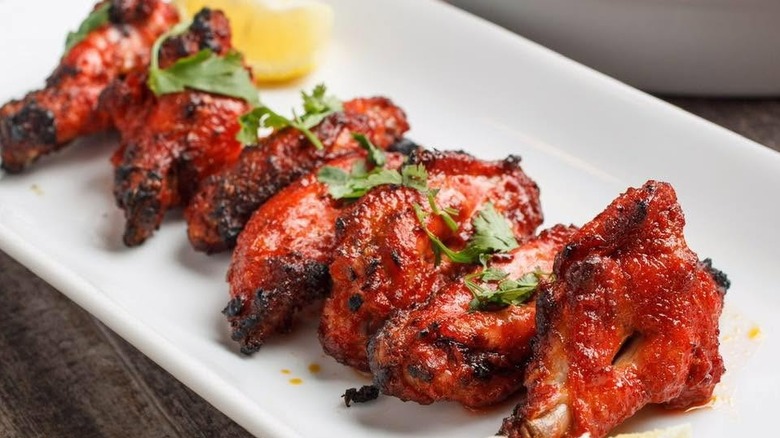 Chicken tikka masala on a rectangular white plate garnished with fresh herbs and a lemon wedge