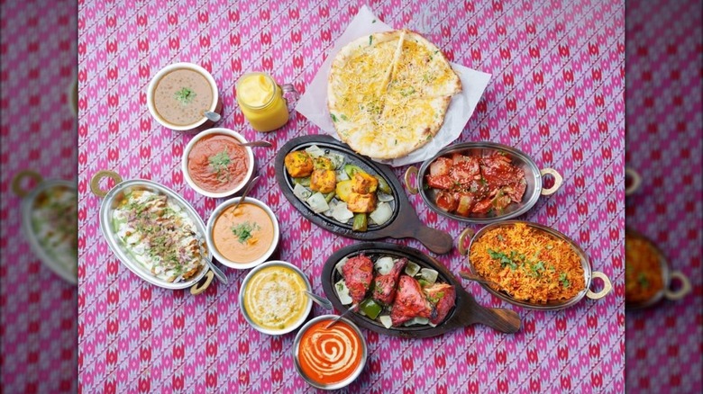 A big spread of delicious Indian food, including tandoori chicken, rice, naan, and various chutneys from Spice Up, House of Indian Cuisine