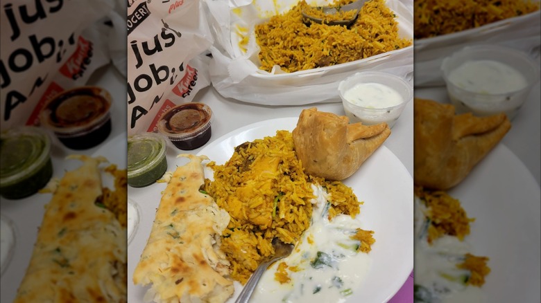 A big plate of food from Taj Mahal Restaurant, including rice, samosa, and dipping sauces