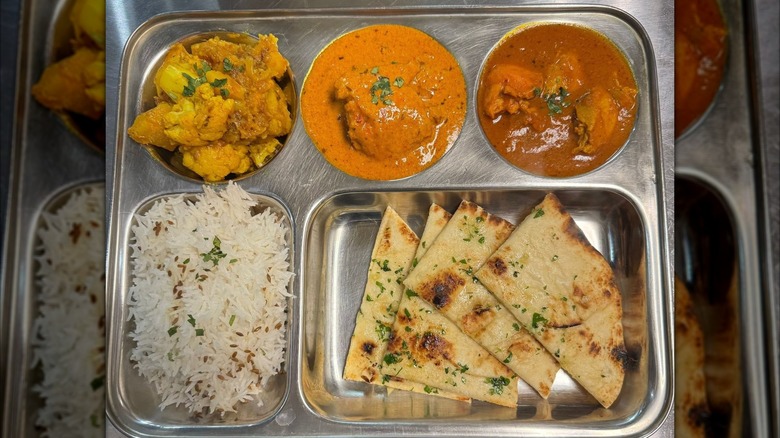 A thali with rice and naan on a metal serving platter at Shagan's