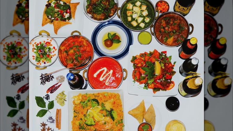 Delicious Indian eats from Kathmandu Kitchen and Bar spread out on a white tablecloth, including curries and saag paneer