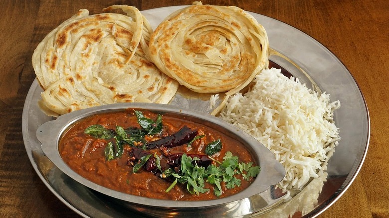 Madras chicken curry on a silver platter with rice and naan