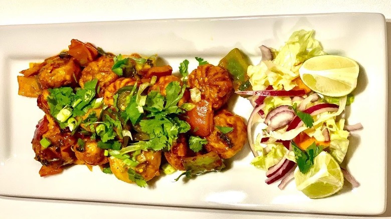 Chili chicken momo and salad on a white, rectangular plate from Cafe Everest