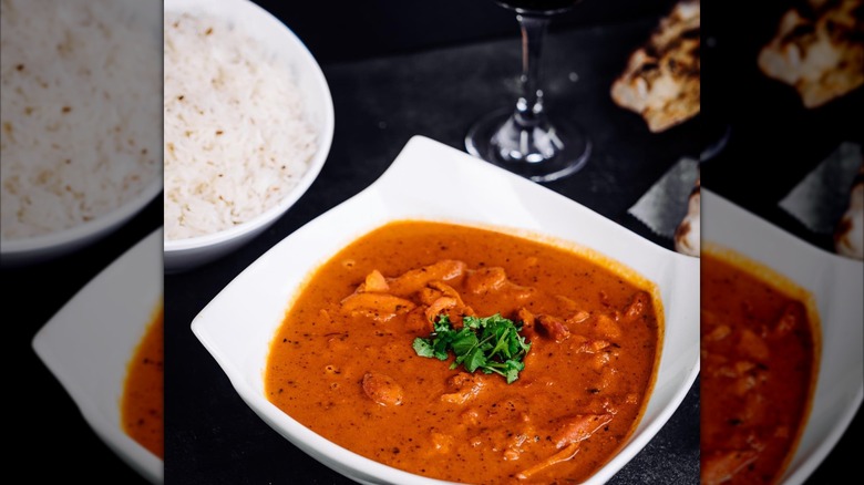 A delicious buttery curry in a white bowl with rice on the side from Shahi Palace India Grill