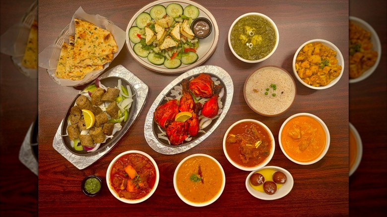 A spread of Indian food, including curries, naan, and rice in individual bowls