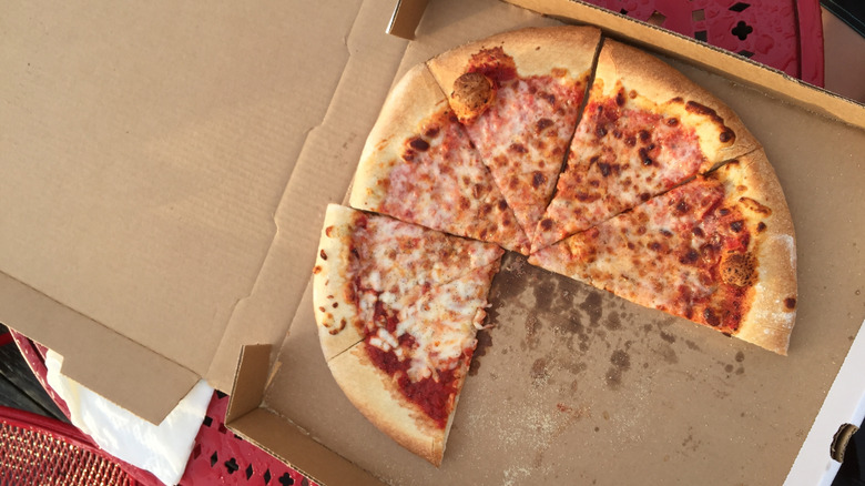 Partially eaten cheese pizza in a to-go box