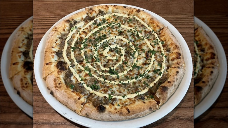 Whole pizza from Camporosso topped with a spiral-shaped drizzle of white sauce