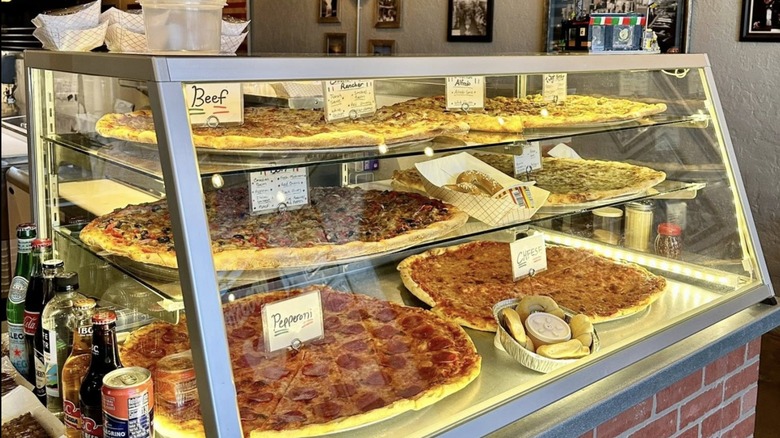 Glass display case at DiCintio's Pizza Cucina filled with various pizzas for sale
