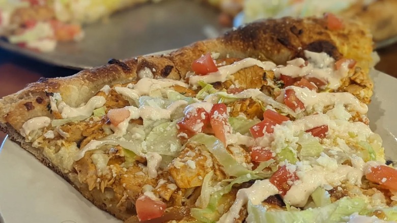 Slice of Pizza special called Chicken Tostada, with braised Southwestern chicken, spicy Rojo sauce, chipotle crema, lettuce, tomato, cilantro, queso Cotija, mozzarella from Dr. Ho's Humble Pie