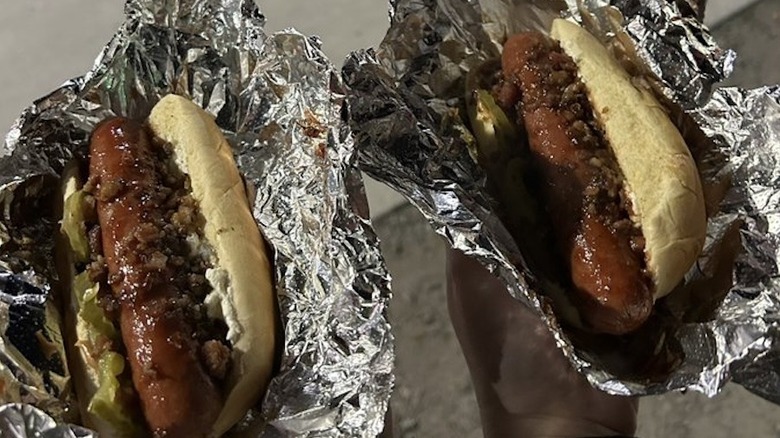 hands holding two hot dogs in foil from The Dog House in Tulsa