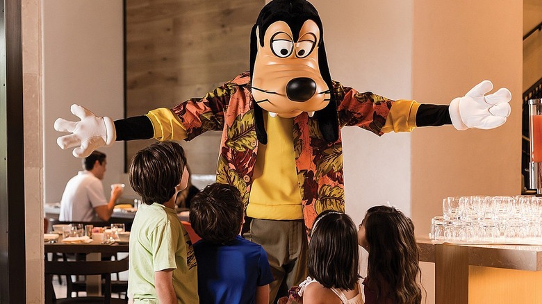 A group of children at the restaurant get in to hug Goofy