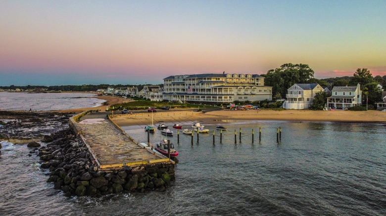 A long shot of the hotel with a boat jetty in the foreground and a number of little boats near the beach