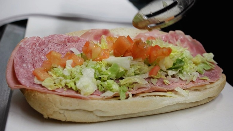 An Italian sub maker adds tomatoes at Jeannotte's in Nashua