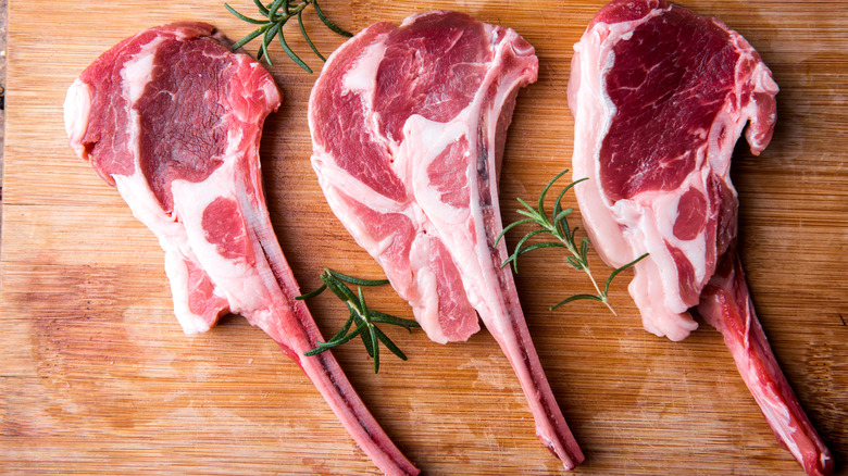 Raw lamb chops on a wooden cutting board.