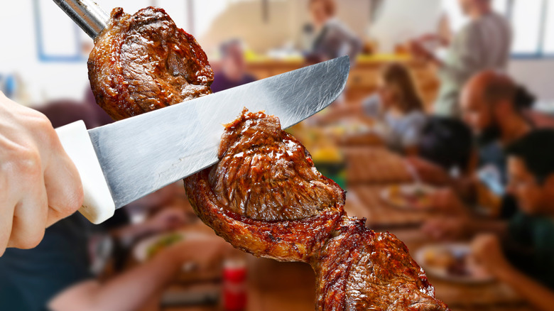 slicing steak with knife at brazilian steakhouse