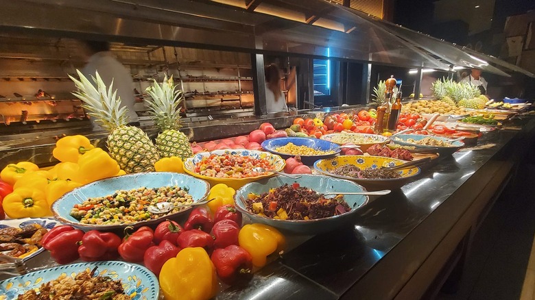 Bowls of food line a long table decorated with pineapples.