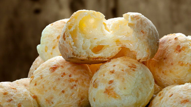 Pile of small rolls with the top one cracked open to see the melted cheese inside.