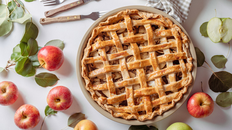 An apple pie with a flaky lattice top sitting on a table.