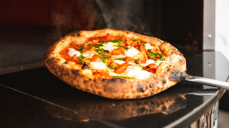 Neapolitan pizza being removed from oven