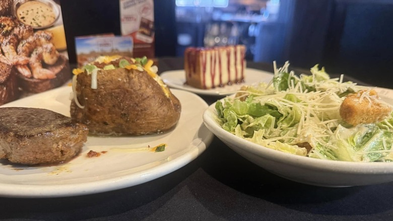Outback steak with loaded baked potato, salad, and cheesecake