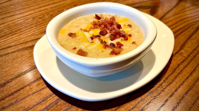 Outback loaded baked potato soup in a white bowl on a wooden table