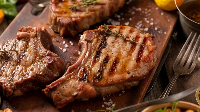 Cooked pork chops on cutting board next to fork