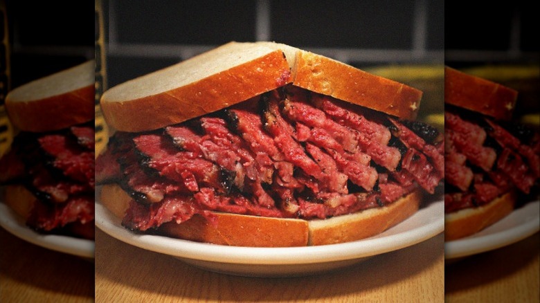 Close up of stacked pastrami sandwich on white plate at Katz's Deli