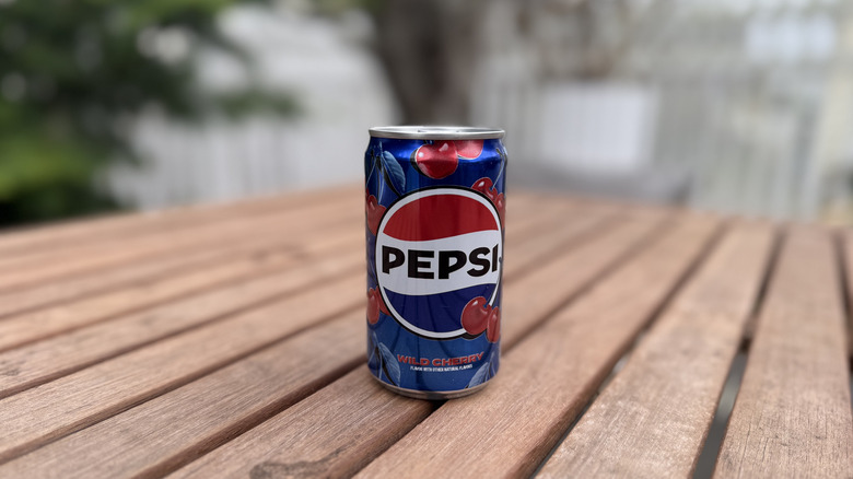 Can of Wild Cherry Pepsi on wooden table in backyard