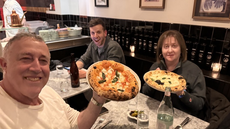 customers holding up pizzas