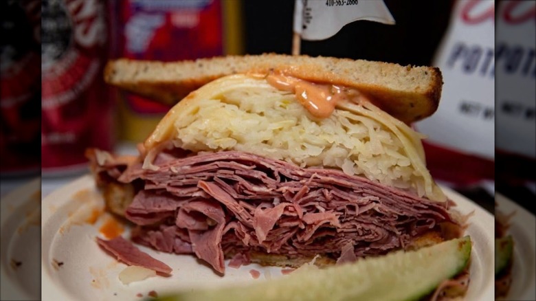 Reuben sandwich on paper plate with pickle