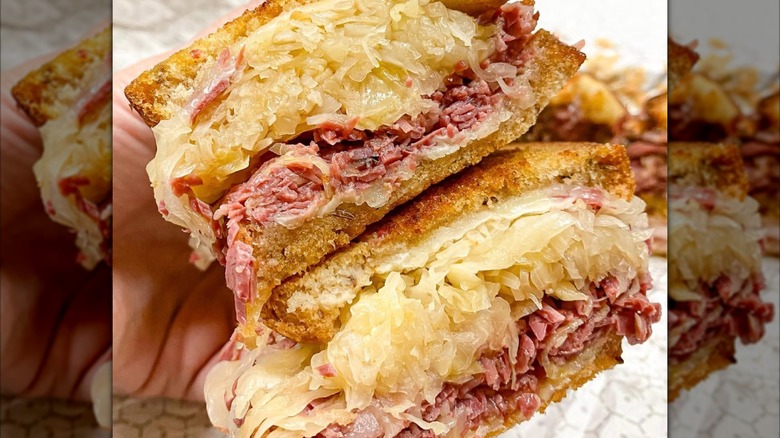 A hand holding a Reuben cut down the middle