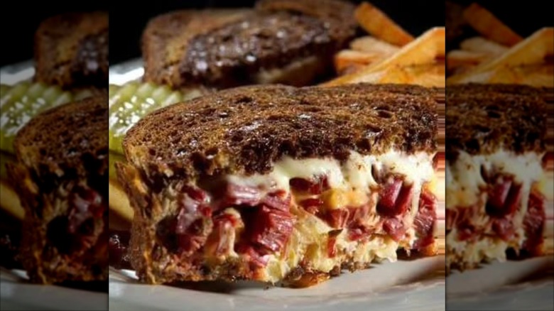 Reuben cut in half with fries on a plate