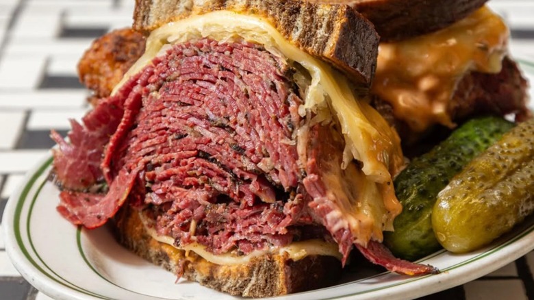 Close up of Reuben sandwich with pickles on a plate