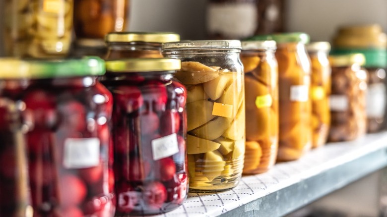 A row of jarred pickled vegetables on a pantry shelf