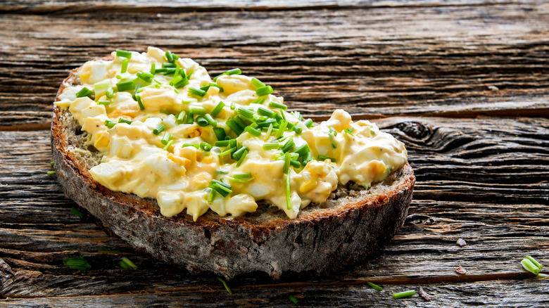egg salad on dark wheat bread on a rustic wooden table
