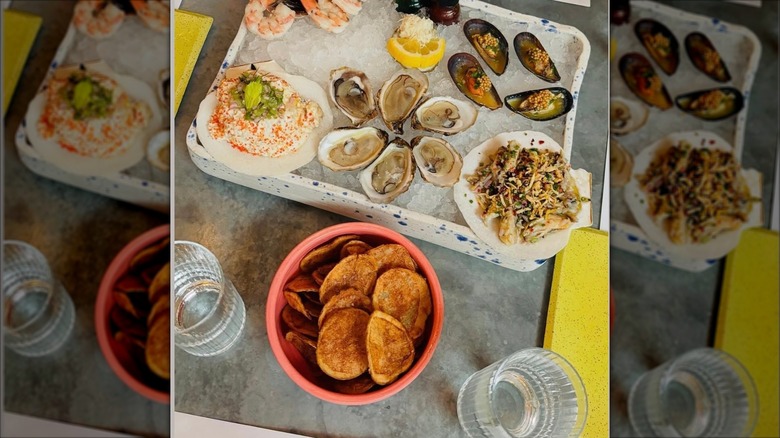 Seafood platter on ice with side of chips and two glasses of water