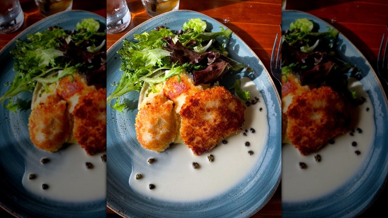 Alaskan halibut cheeks with side of salad on white and blue plate