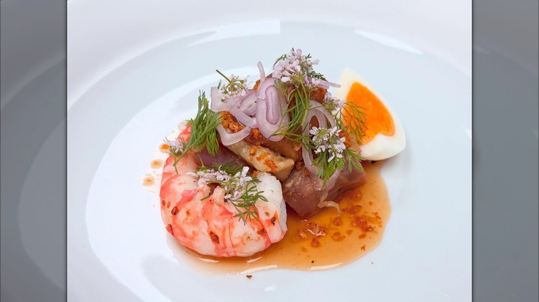 Fancy plated shrimp with hardboiled egg, herbs, red onion, and red sauce