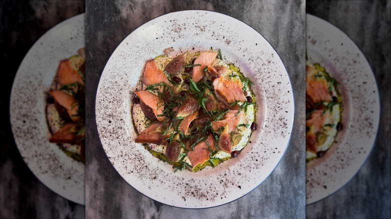 Smoked salmon and figs on creamy spread on white plate