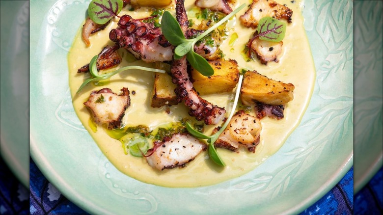 Sliced octopus on top of cream sauce with greens